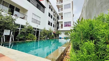 Una piscina al aire libre, sombrillas, sillones reclinables de piscina