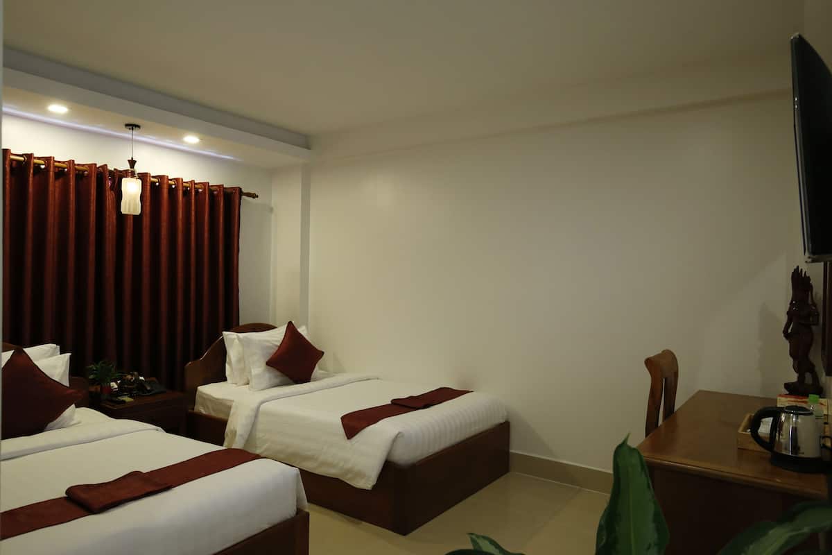 A hotel room with two beds, a wooden desk, a television, and a coffee maker.