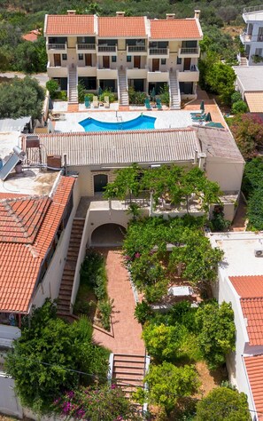 A multi-story hotel with a rooftop pool, outdoor seating, and a landscaped garden.