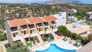 A multi-story hotel with a swimming pool, outdoor seating, and a view of the sea. - Orestis Hotel Apartments (Chania)