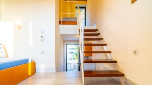 A modern interior with a staircase leading to an upper floor, a reception area with a counter, and a view of the outdoors. - Orestis Hotel Apartments (Chania)