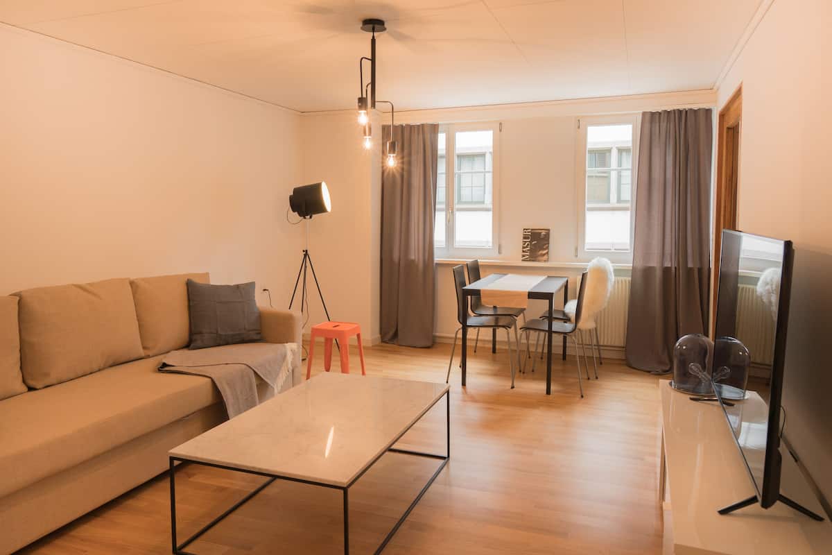 A modern living room with a sofa, coffee table, and dining area.