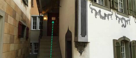 A narrow alleyway with a staircase leading to a door marked "Neugasse 19".