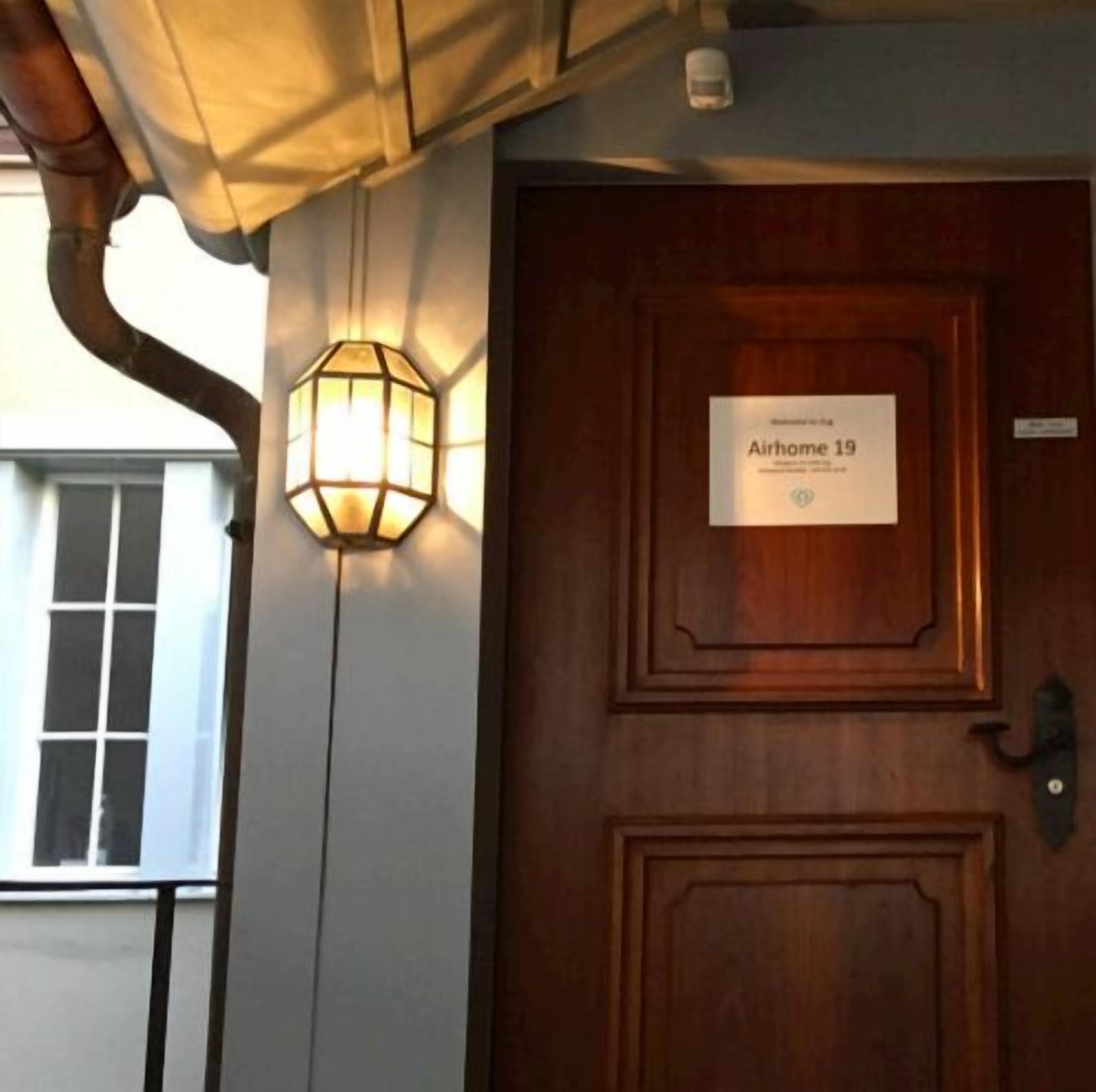 Una porta de fusta amb un senyal que diu "Airhome 19" i un fanal fixat a la paret.