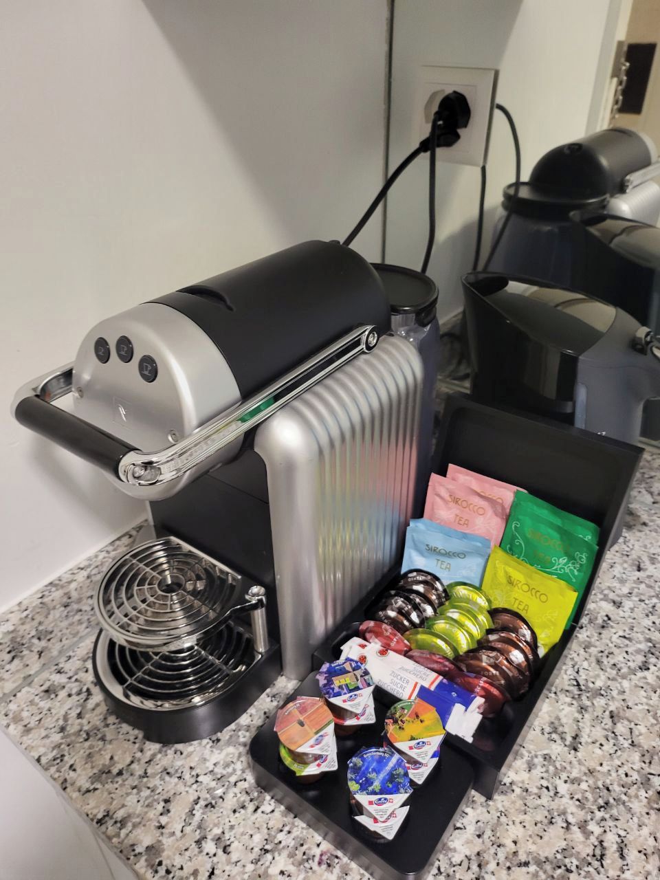 A coffee maker with a drip tray and a selection of tea bags on a countertop.