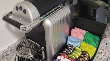 A coffee maker with a drip tray and a selection of tea bags on a countertop.