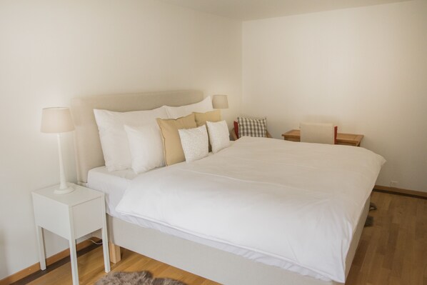 A neatly arranged bedroom with a large bed, two bedside tables, and a lamp on each side. - Stylish Apartment in the Heart of Zug by Airhome (Zug)