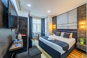 Una habitación de hotel moderna con una cama grande, un escritorio con hervidor, un televisor y una mesita con aperitivos.