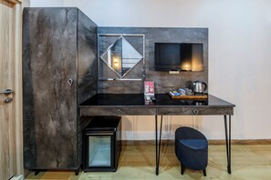 A compact room with a built-in wardrobe, a small kitchenette, a flat-screen TV, and a single chair. - La Pazza Suites (Istanbul)