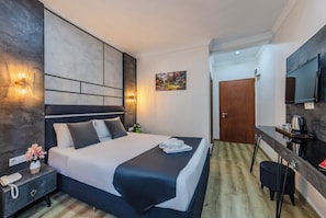 A modern hotel room with a large bed, bedside table, lamp, and a flat-screen TV mounted on the wall. - La Pazza Suites (Istanbul)