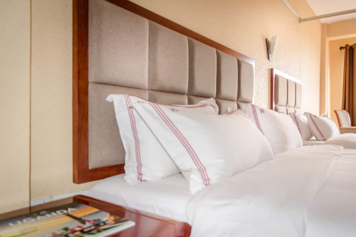 A hotel room with a large bed, a wooden headboard, and a bedside table with a magazine.