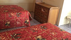 A bedroom with two beds, a wooden dresser, a television, and an air conditioning unit. - Shelton Motel (Rio Grande)
