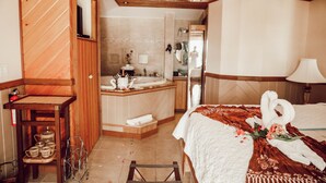 A hotel room with a wooden interior, a bed with a white and brown bedspread, a bouquet of flowers, and a towel sculpture. - EMBRACE Resort (Staniel Cay)