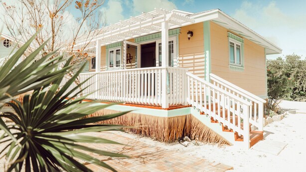 A two-story house with a covered porch and a staircase leading to the second floor. - EMBRACE Resort (Staniel Cay)