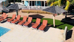 A two-story building with a balcony, a swimming pool with lounge chairs, and palm trees. - EMBRACE Resort (Staniel Cay)