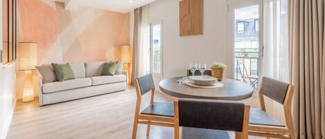 A modern living room with a sofa, dining table, chairs, and a view of the outside.