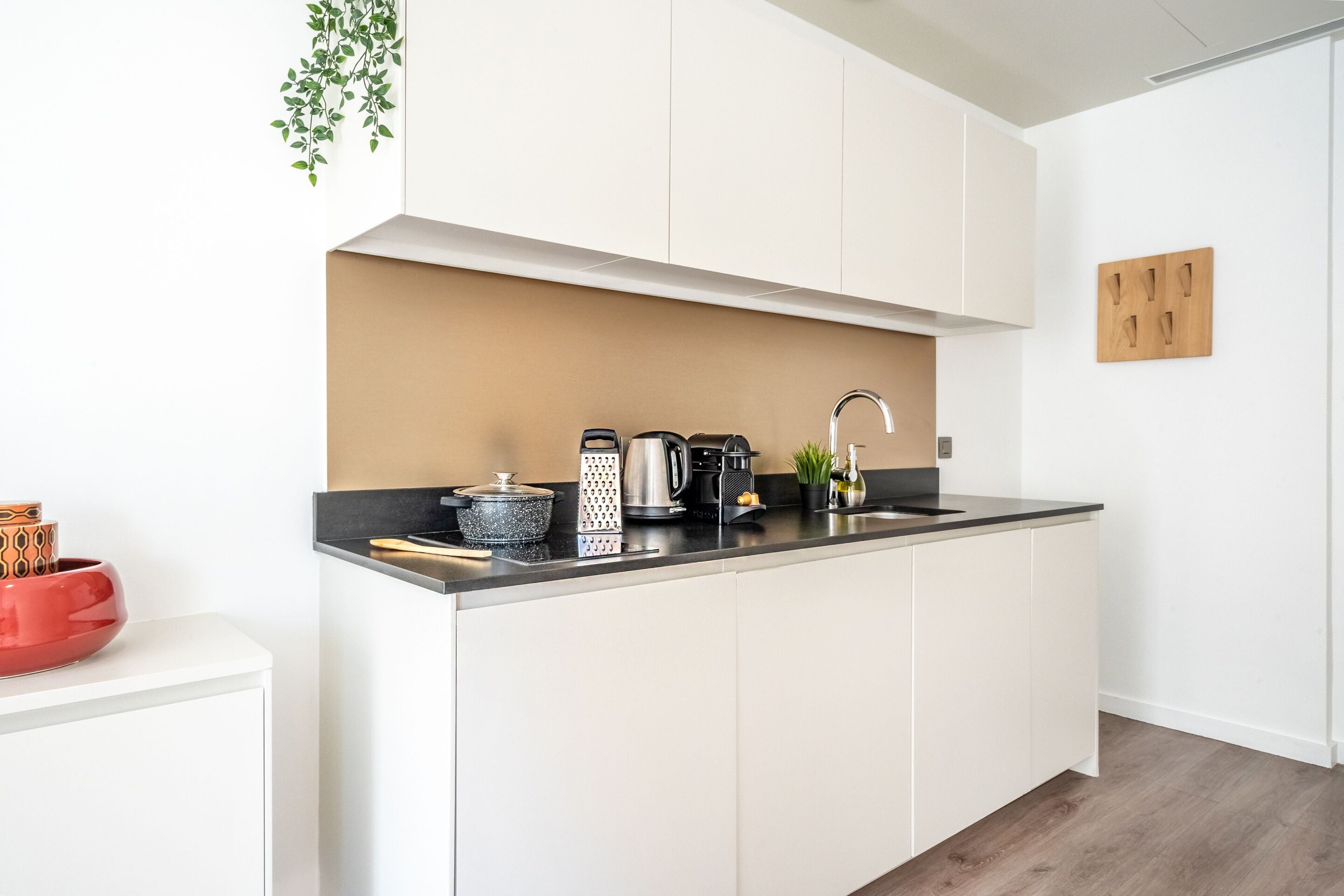 Una cocina moderna con armarios blancos, encimera negra y diversos electrodomésticos.