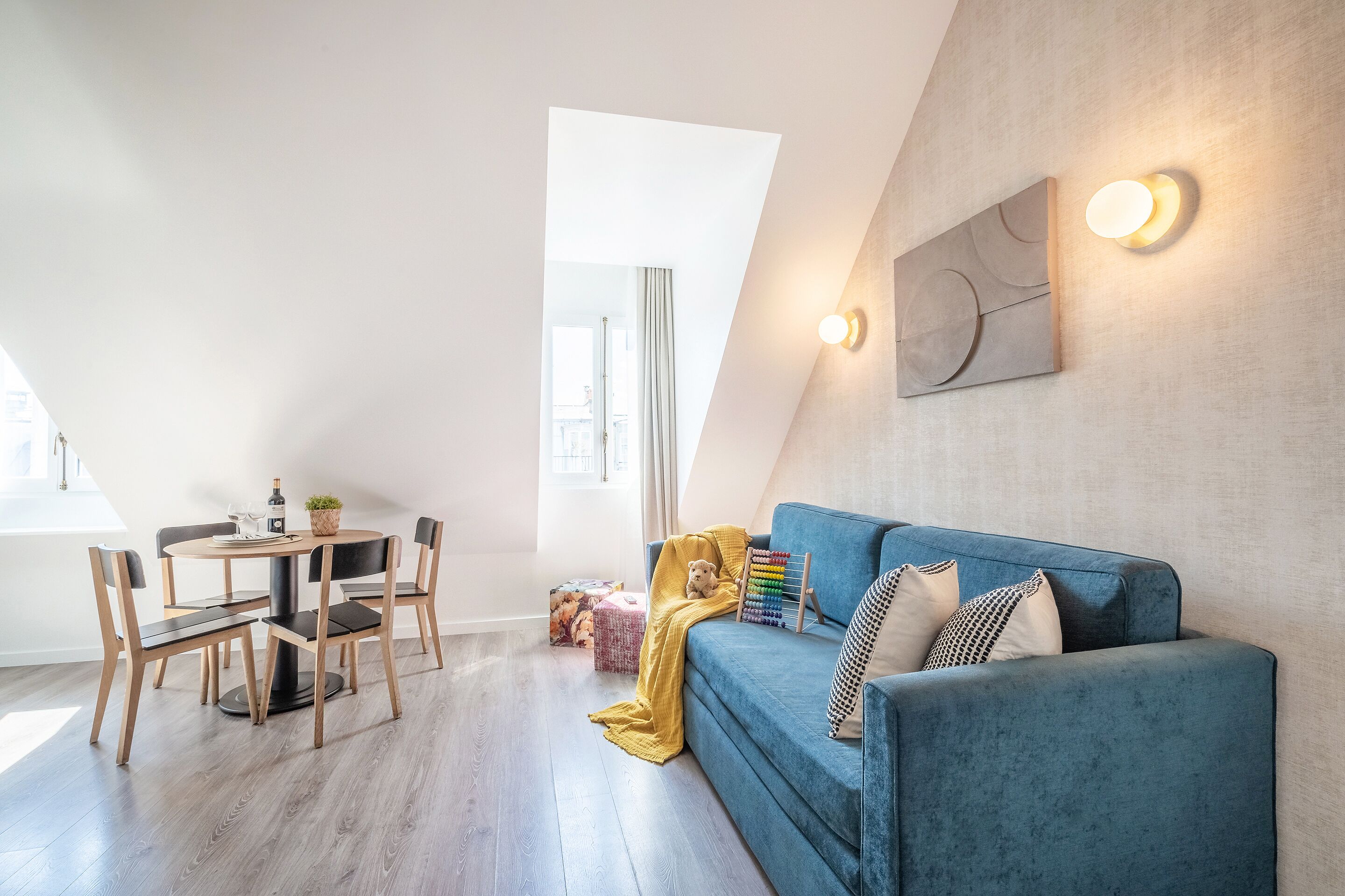 Un loft moderno con comedor, sofá y una lámpara fijada a la pared.