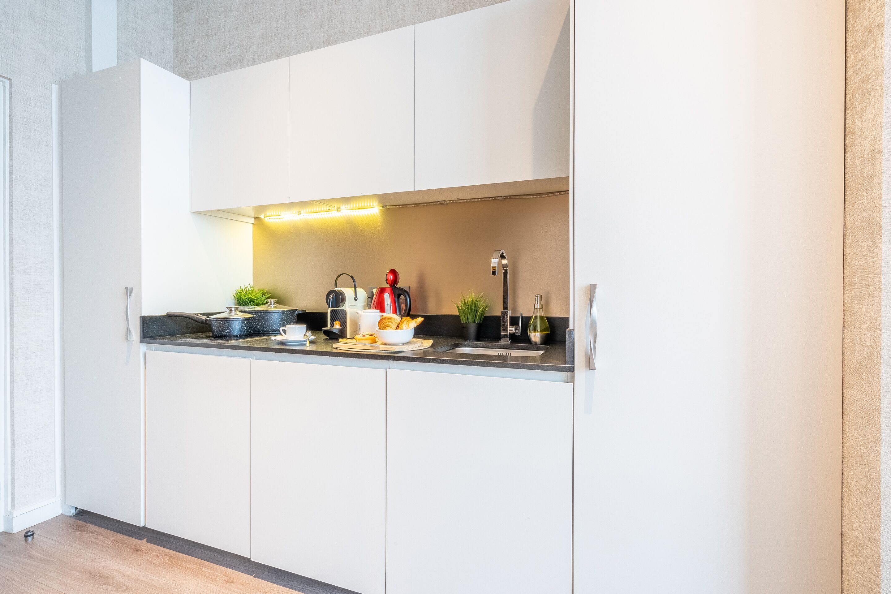A modern kitchen with white cabinets, a black countertop, and various appliances.