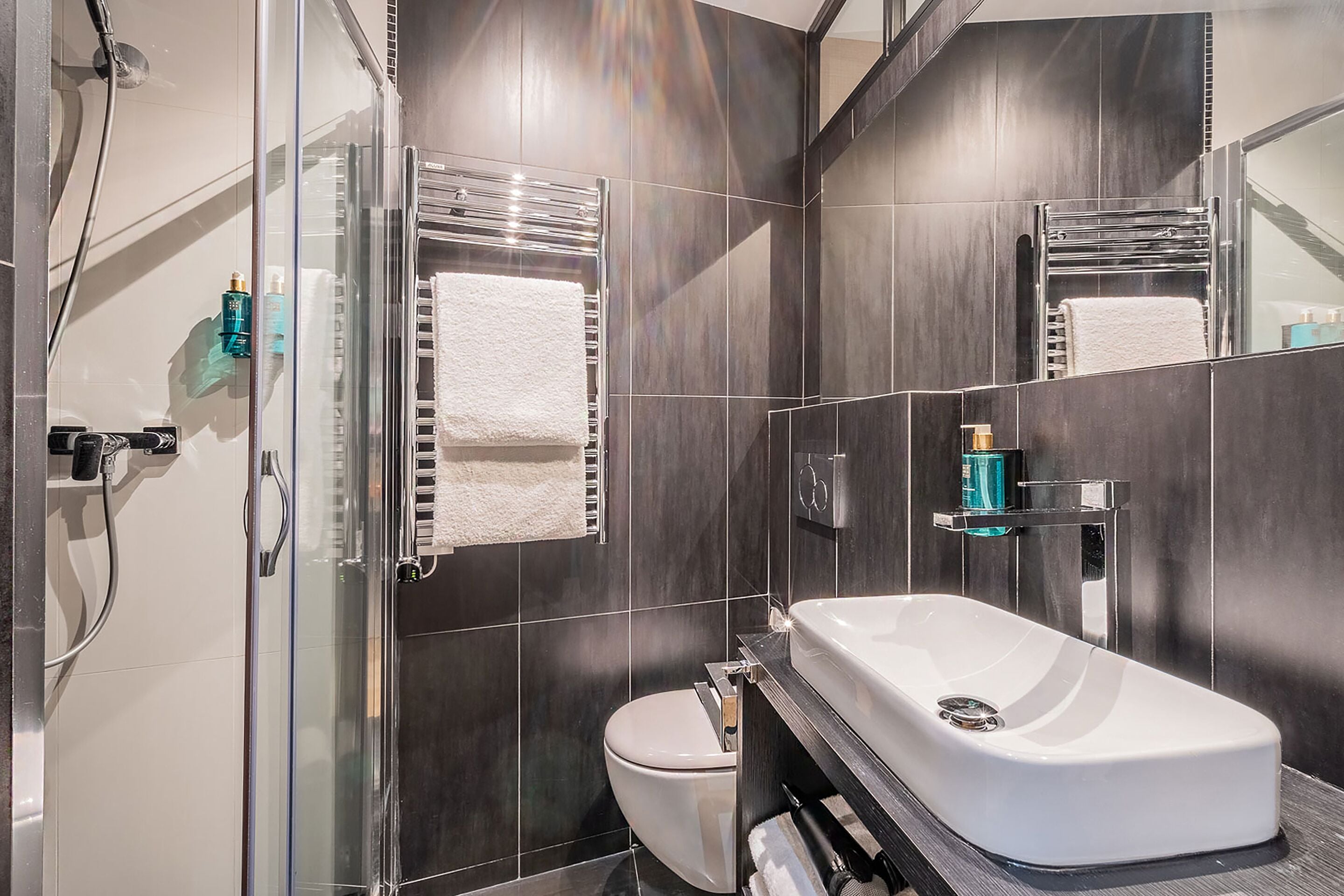 A modern bathroom with a glass shower enclosure, a white toilet, and a white sink with chrome fixtures.
