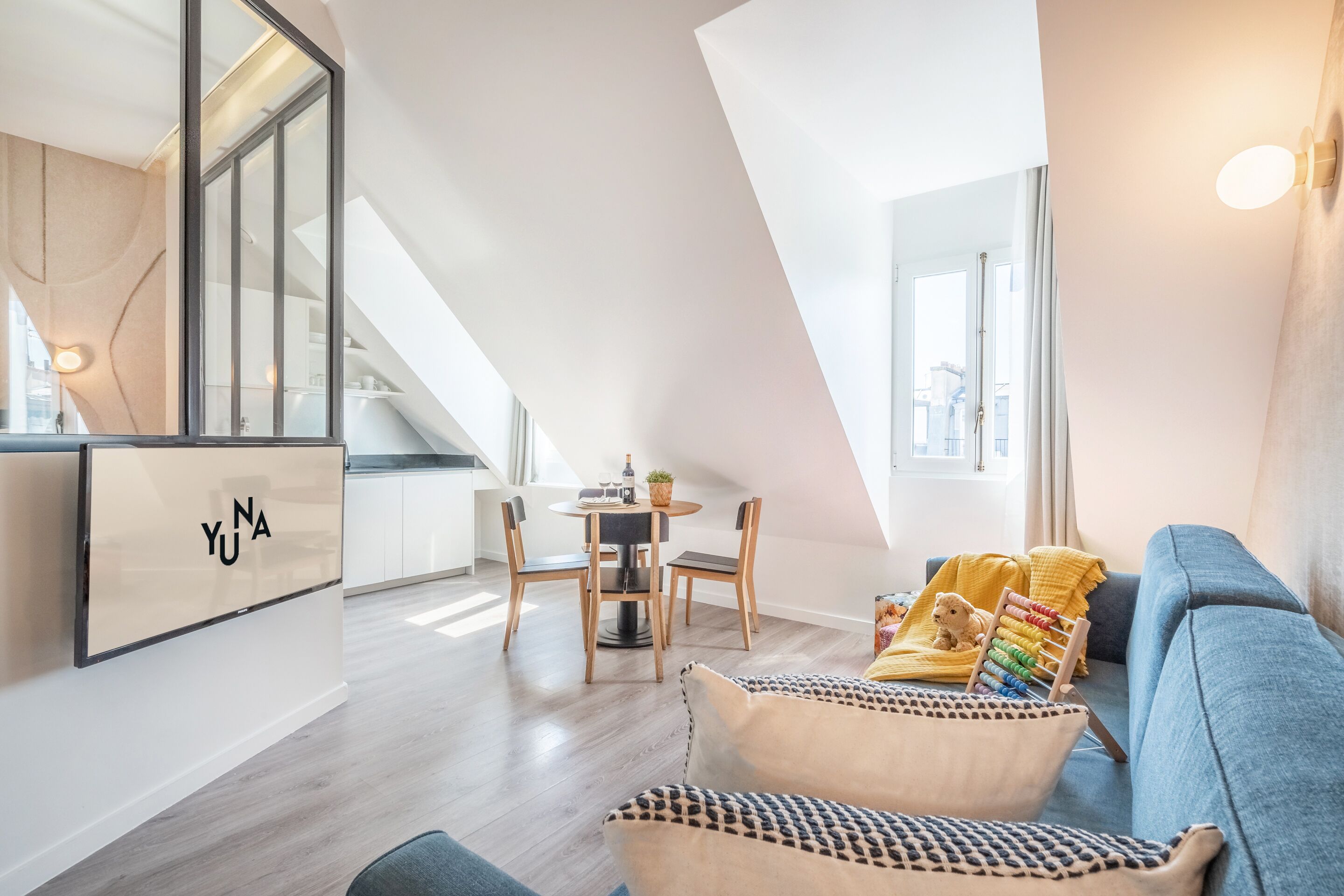 A modern loft apartment with a dining area, a sofa, and a staircase.