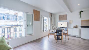 Un appartement moderne doté de grandes fenêtres, d’un coin repas et d’une cuisine.