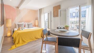 Una habitación de hotel moderna con una cama, una mesa de comedor y un balcón con vistas.