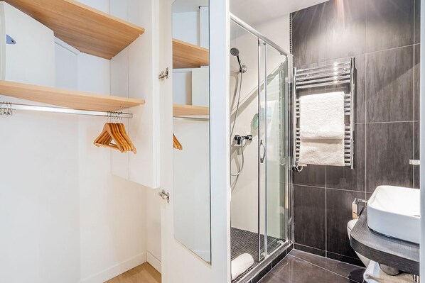Un bagno moderno con cabina doccia in vetro, un lavandino bianco e un porta asciugamani.