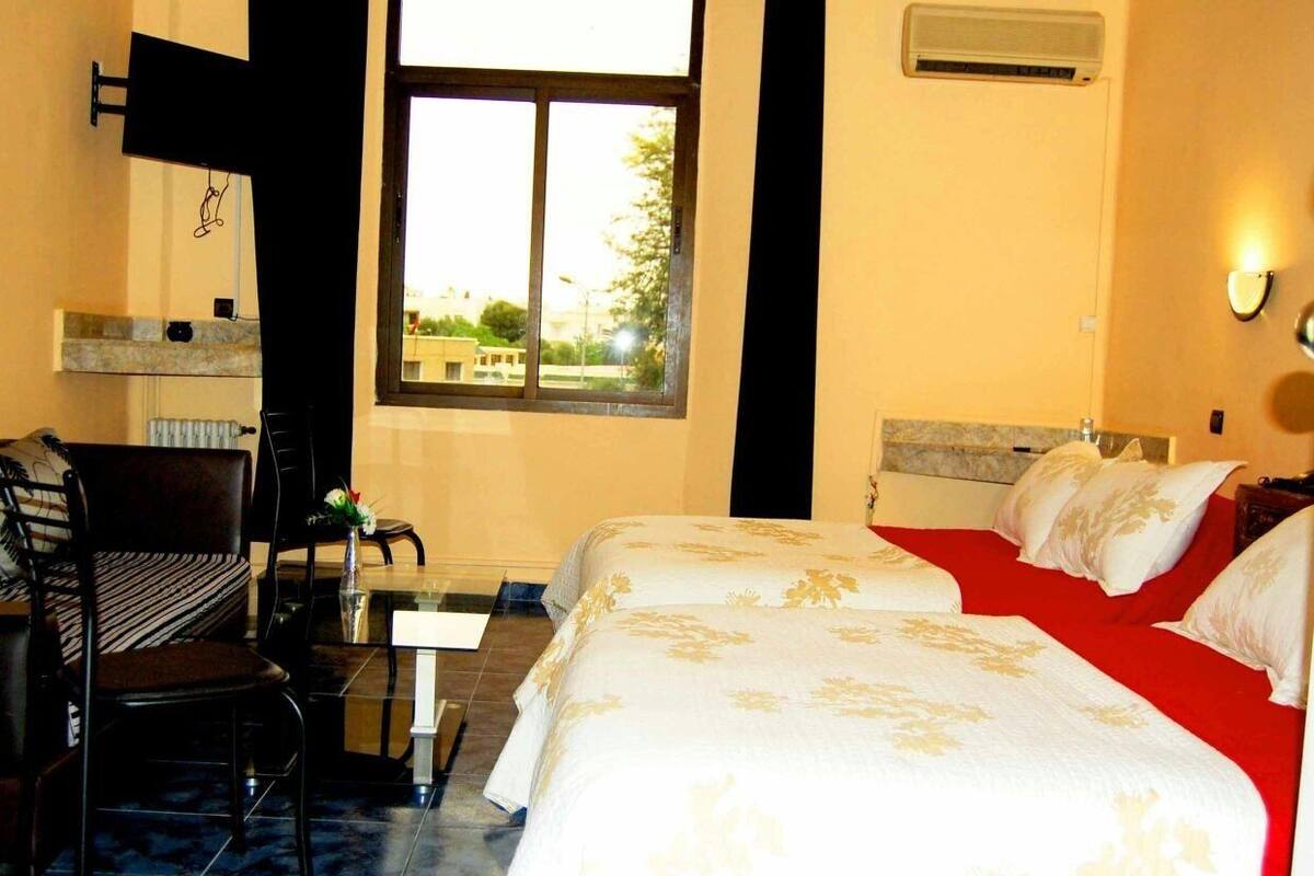 A hotel room with two beds, a desk, and a chair.