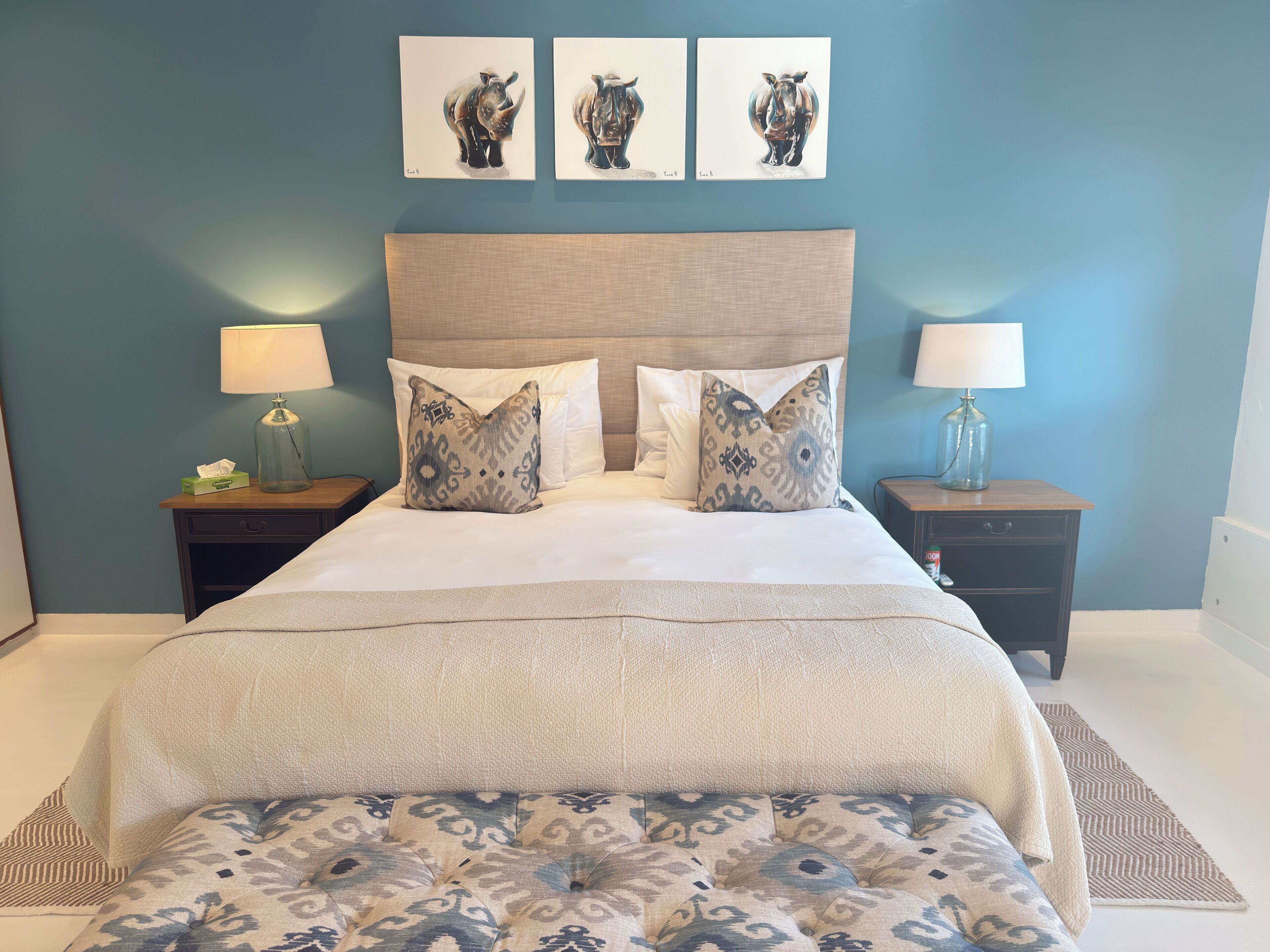 A neatly arranged bedroom with a large bed, two nightstands, and three wall-mounted artworks.