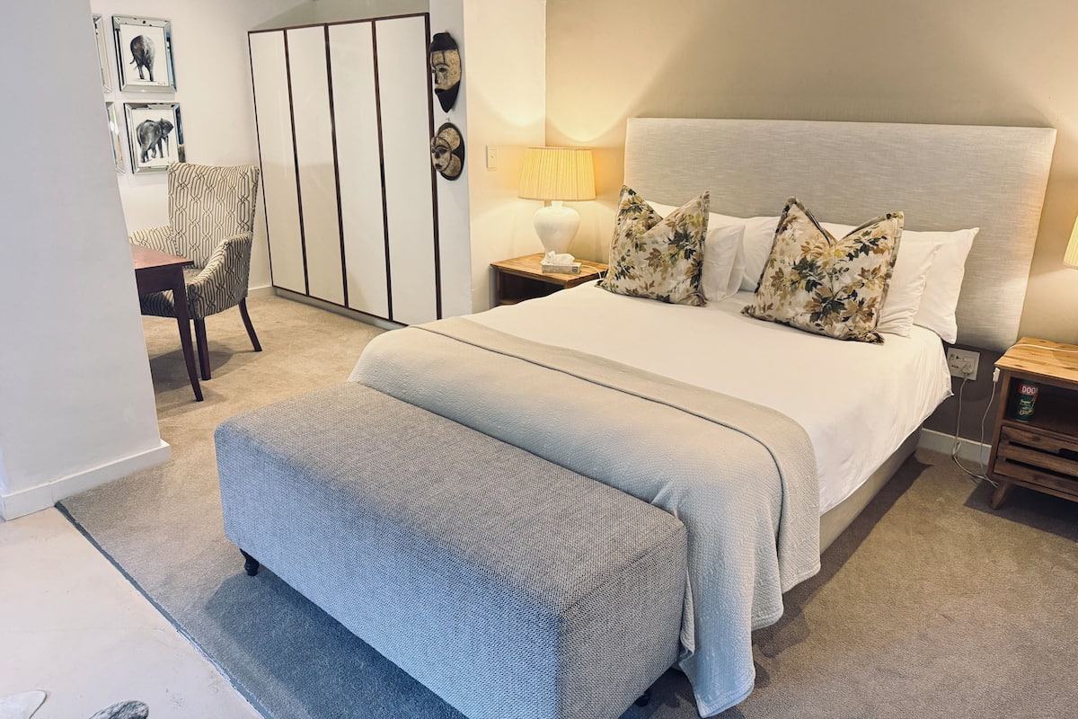 Une chambre à coucher avec un grand lit, une table de chevet, une lampe, une chaise et une armoire.