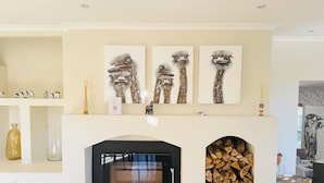 A modern living room with a fireplace, a wooden coffee table, and a stack of firewood. - Residence Vive La Vie (Franschhoek)