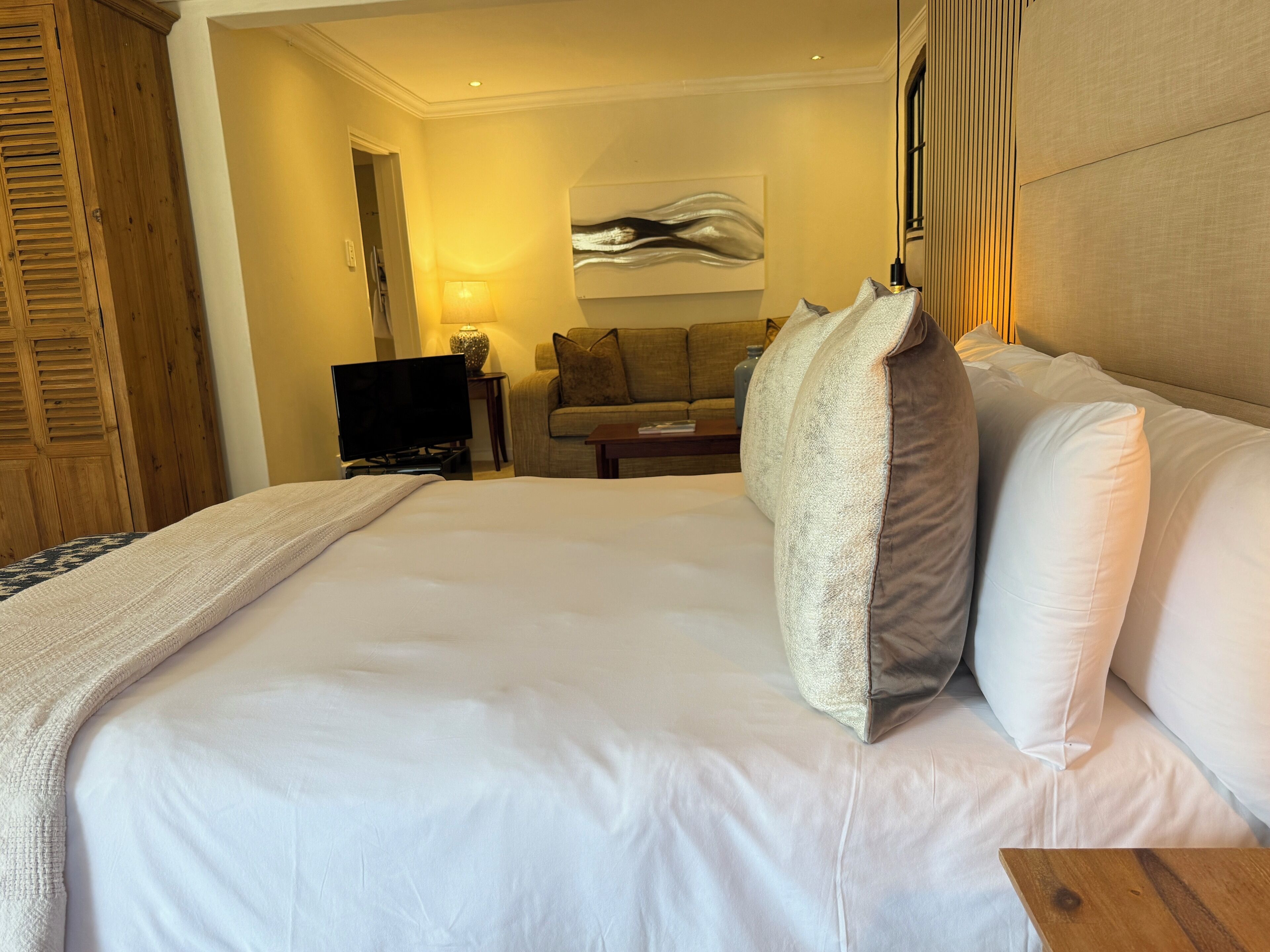 Ett hotellrum med en stor säng, en tv, en soffa och en tavla på väggen.