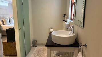 A compact bathroom with a white sink, a mirror, and a small window.