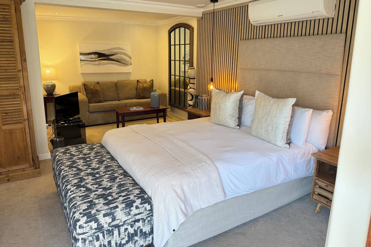 Une chambre moderne avec un grand lit, un canapé et un téléviseur.