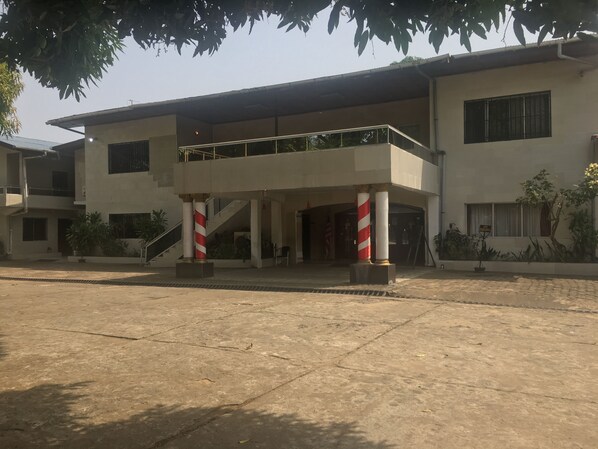 A building with a flat roof, a balcony, and a staircase leading to an upper level.