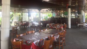 Un restaurante con terraza, columnas blancas y una zona de bar.