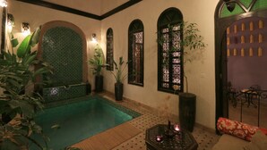 A traditional Moroccan interior with a swimming pool, arched windows, and decorative plants. - Riad Houdou (Marrakech)