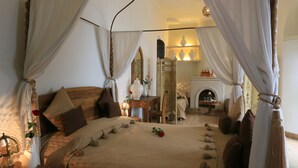 A bedroom with a large bed, draped curtains, a wooden headboard, a nightstand with a lamp, and a mirror. - Riad Houdou (Marrakech)