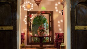 A corridor with a central table, two chairs, and a decorative mirror reflecting greenery. - Riad Houdou (Marrakech)