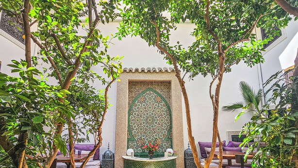 A courtyard with a fountain, seating area, and decorative wall. - Riad Houdou (Marrakech)