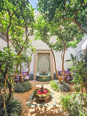 A courtyard with a fountain, seating area, and decorative wall.