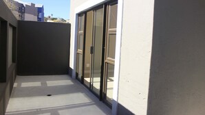 A narrow outdoor corridor with a glass door leading to a balcony. - Discovery Riverlets Apartment (Windhoek)
