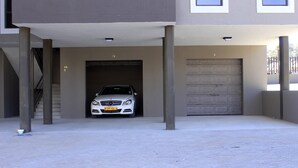 A building with two garage doors, one with a car parked inside and the other closed. - Discovery Riverlets Apartment (Windhoek)