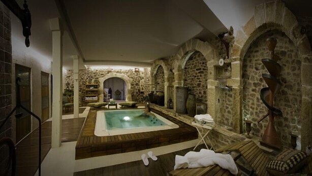 A spa room with a central hot tub, stone walls, and wooden furniture. - El Morendal (Almarza)