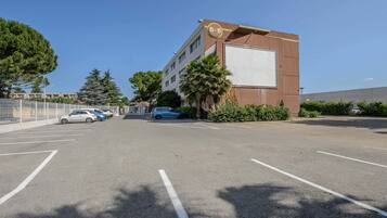 A parking lot with several cars, a building with a large sign, and a clear blue sky.