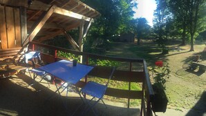 Un área de patio al aire libre con cubierta de madera, una mesa y sillas.