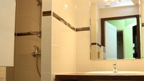 Une salle de bain avec un grand miroir, un lavabo et une douche.