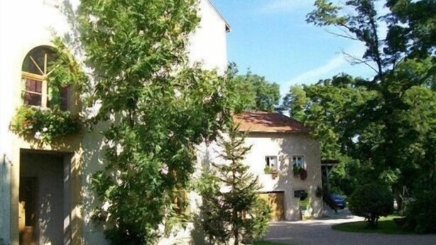 Un edificio de dos plantas con fachada blanca y tejado de tejas rojas.