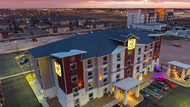 A multi-story hotel with a prominent 'My Place' sign, a parking lot with marked handicapped spaces, and a view of the surrounding area.